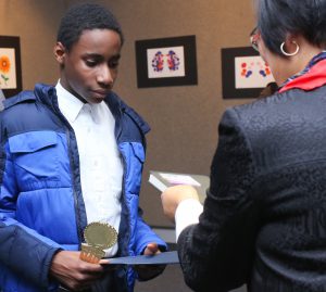 Blackburn Middle School 7th grader Scottie Stewart receives an award for his artwork from Hyun Chong Kim, JSU professor of art and ceramics. (Photo by Anissa Hidouk, JSU)