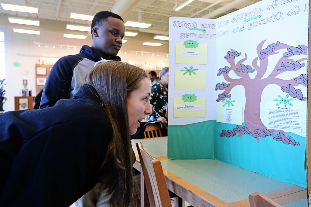 Jessica Kirkendoll, a member of the Society of Women Engineers at JSU, studies an entry by Alex Riley (standing) at the  Blackburn Science Fair. (Photo by Charles A. Smith, JSU)