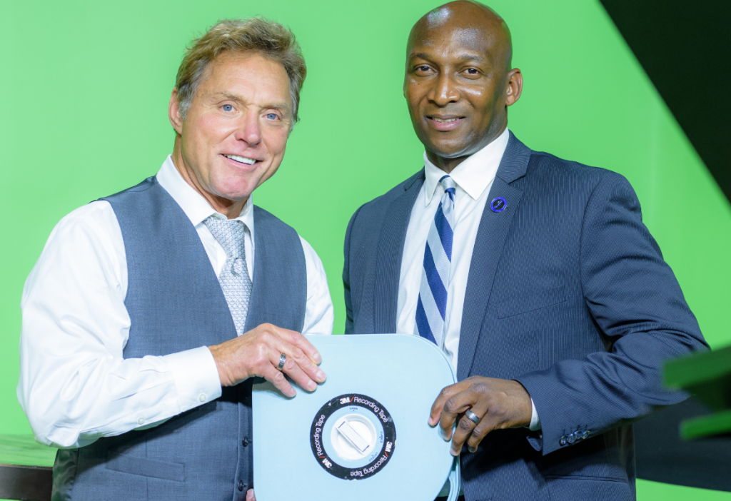 Edward Saint Pé, left, founder of WeatherVision and a JSU broadcast professor of meteorology, presents Anthony L. Holloman, vice president for Institutional Advancement, celebrate a film partnership.
