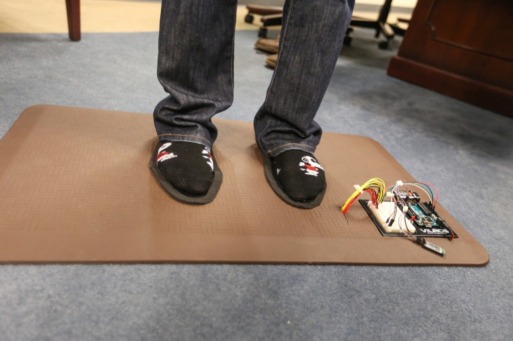 Smart Mat2: Standing on the prototype, Baker shows how the feet are positioned for reading by an Android app. (Photo by Charles A. Smith/JSU)