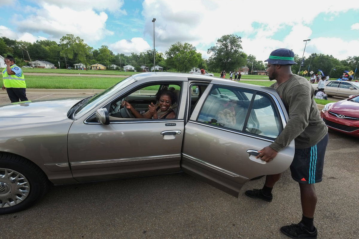 A JSU student volunteer provides curbside service to a motorist. (Photo by Charles A. Smith/JSU)