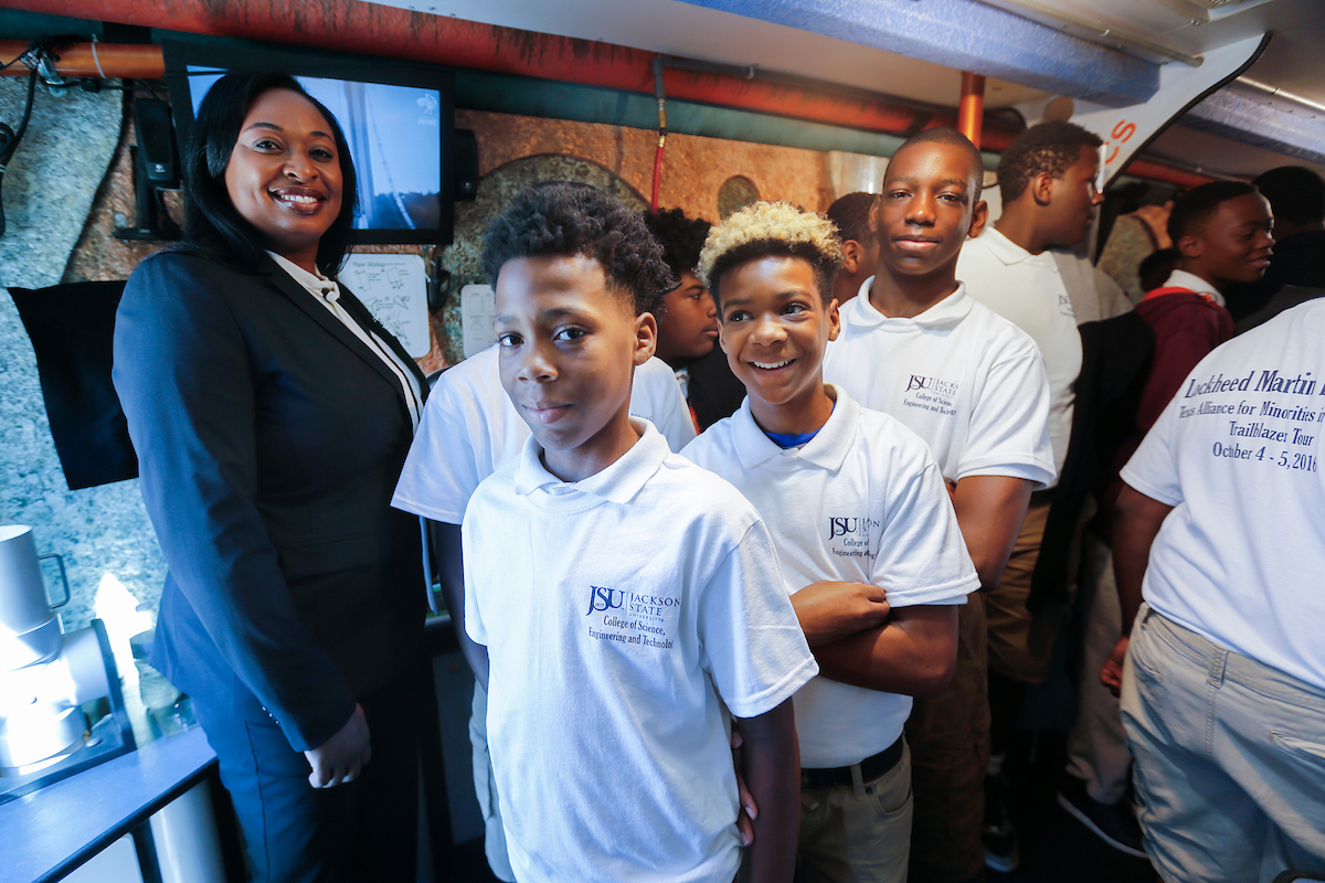JPS students join Lockheed executive and JSU alum Karmyn Norwood inside a science museum on wheels called Trailblazers, parked on the main campus outside. The trailer provides information on energy, space, weather, biotechnology and aerodynamics. (Photo by Charles A. Smith/JSU)