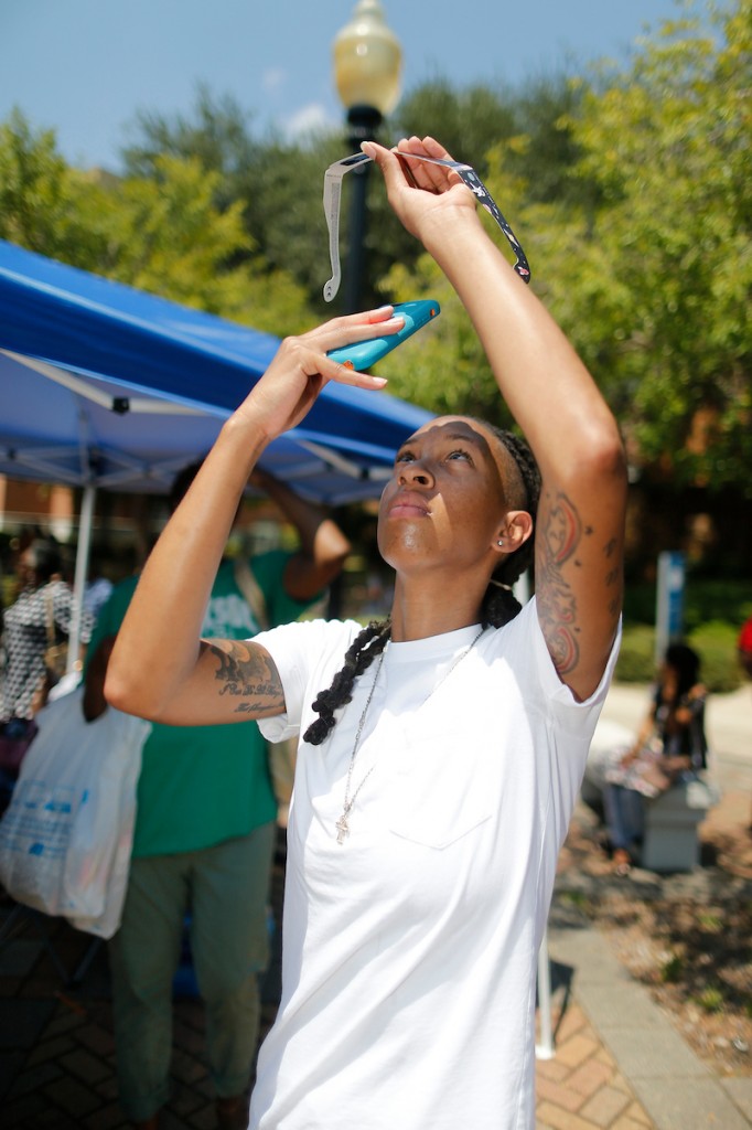 A student uses her mobile phone to snap an image of the eclipse through solar eyewear. (Photo by Charles A. Smith/JSU)