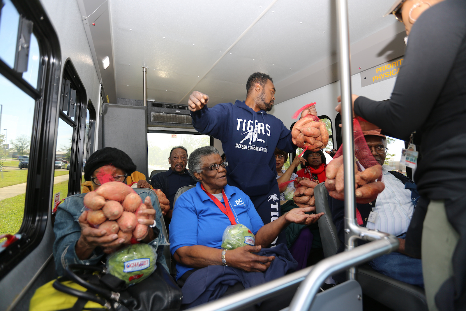 JSU distributes sweet potatoes and lettuce to senior citizens in a public transit vehicle. (Photo by Charles A. Smith/JSU)