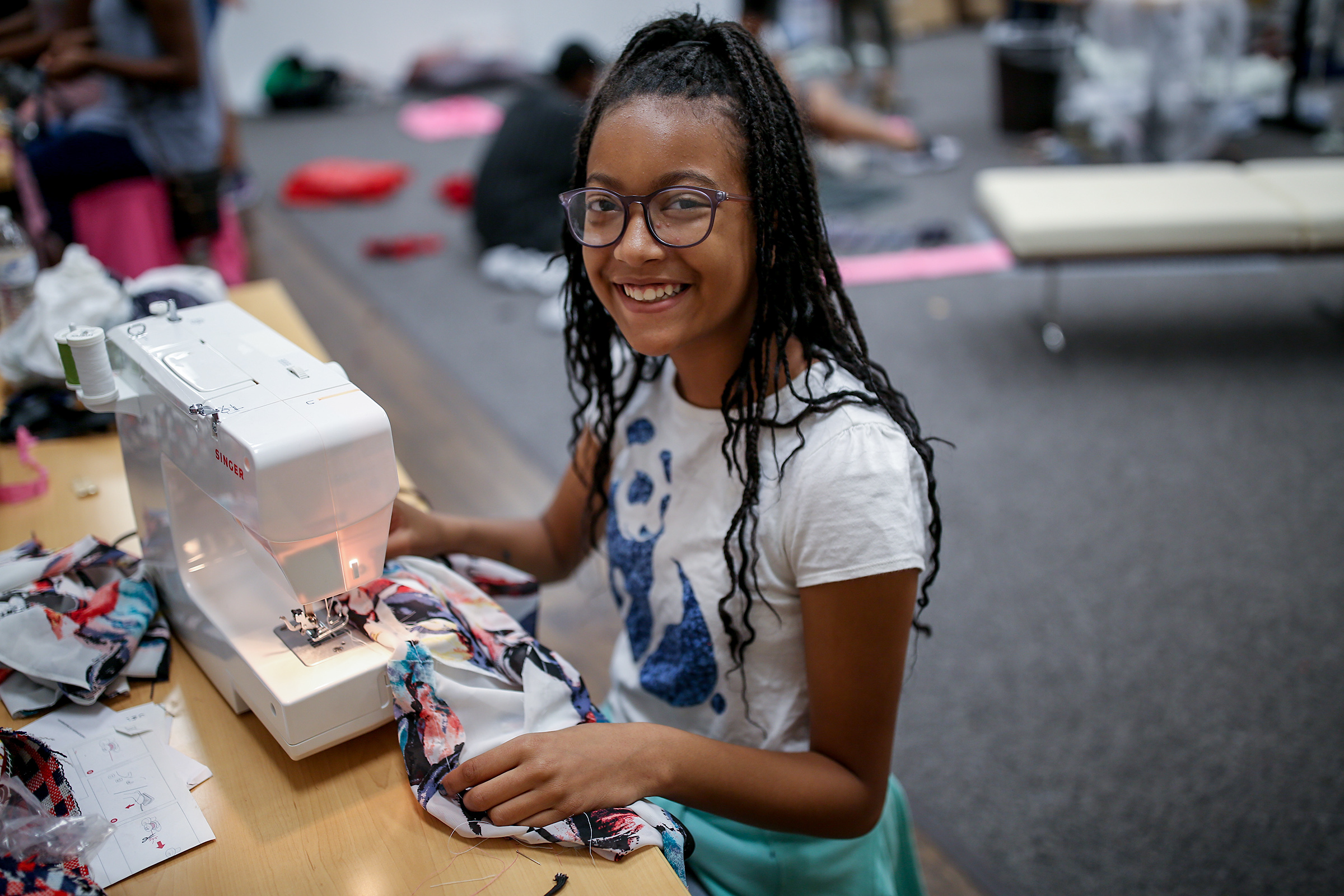 A camper is all smiles as she learns how to use a sewing machine at the "Say it isn't so, I will learn how to sew" summer camp at JSU led by Shonda McCarthy, director of JSU art galleries, and Kristen Martin, an entrepreneur and 2018 graduate of the College of Business. (Photo by Charles A. Smith/JSU)