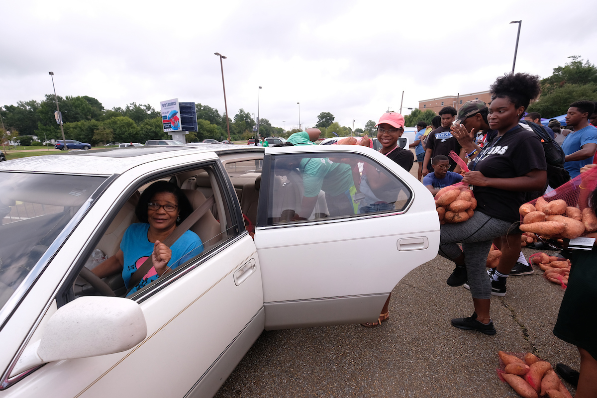 A gleeful patron is eager to receive bags of free sweet potatoes. (Photo by Charles A. Smith/JSU)