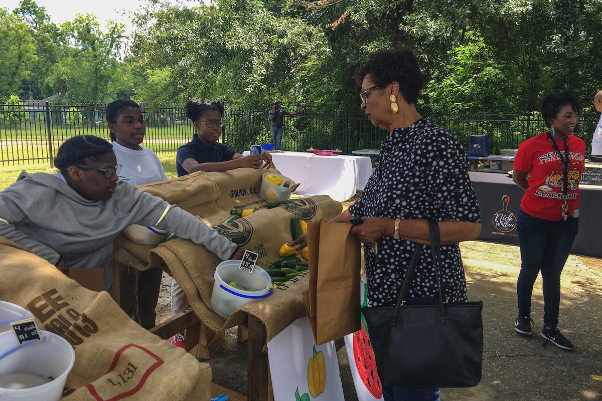 Blackburn Laboratory Middle School students assist a customer with the purchase of vegetables from their student-led Farmers Market. The event was held Wednesday, May 22, in partnership with Jackson State University and supported by sponsors and the community. (Photo by Charles A. Smith/JSU)