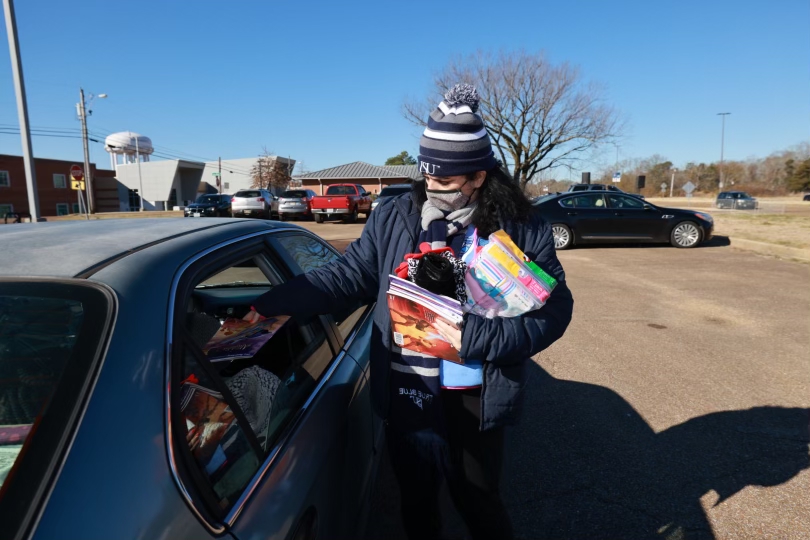 Heather Denne', Ph.D., director of Community Development distributes children's books, hats and gloves during the Crop Drop. Denne' says, "This event keeps me up at night worrying about the well-being of those in our community. I want our community to know we are here to help."