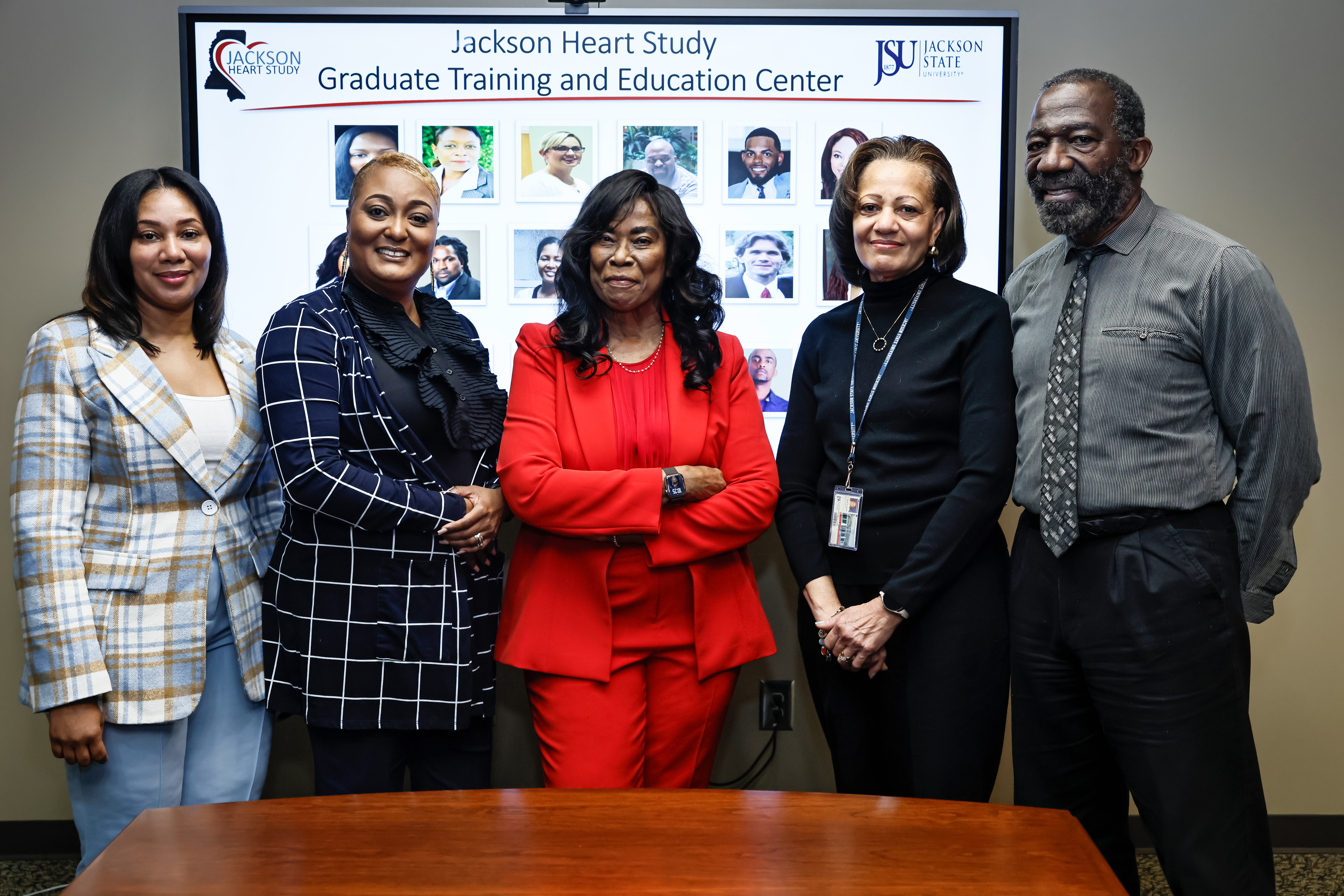 photo of Jackson Heart Study Graduate Training and Education Center faculty and staff standing in front of screen with students from the program on it