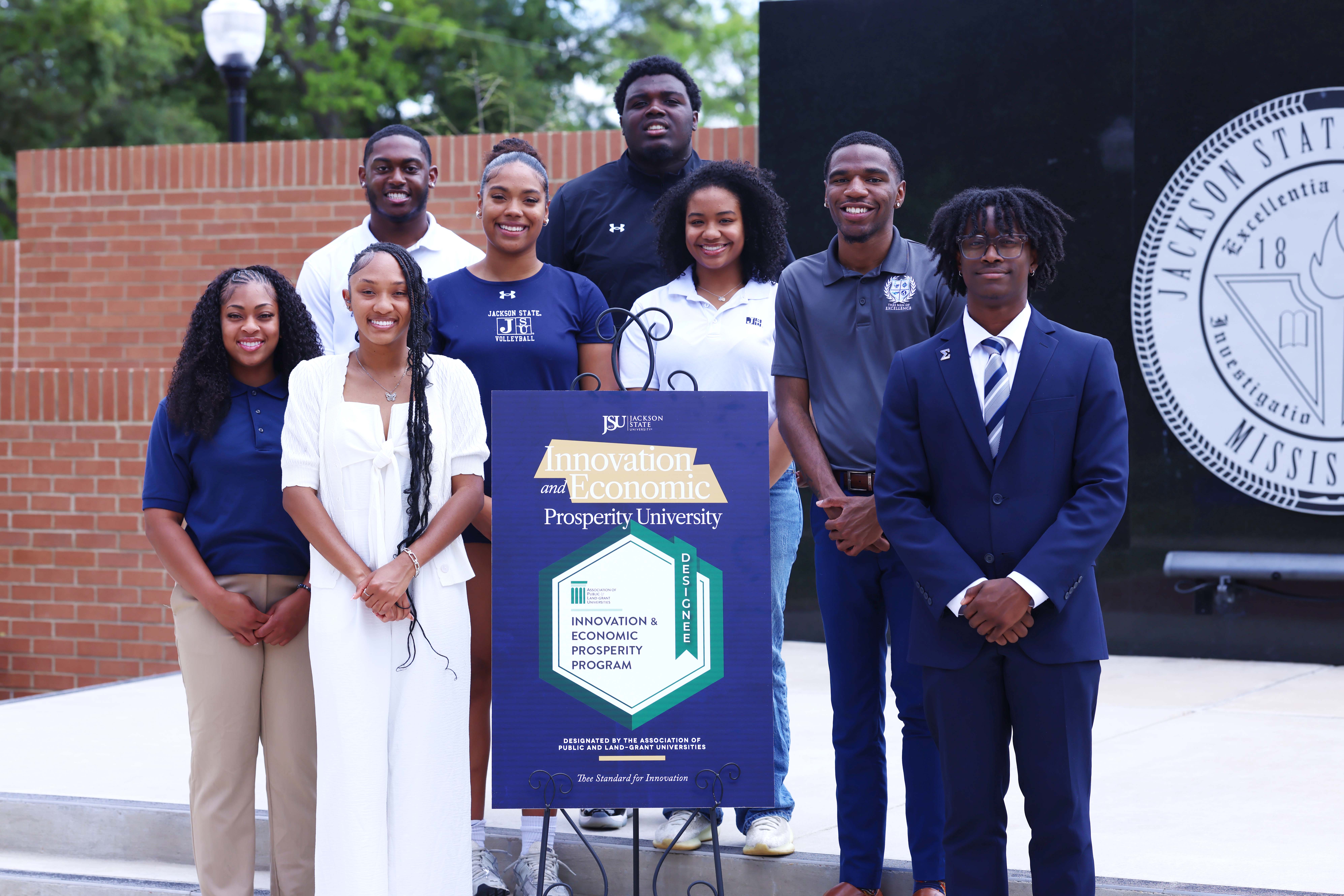 JSU students pose for celebratory photo with sign in honor of the university's new Innovation and Economic Prosperity (IEP) designation from the Association of Public and Land-grant Universities (APLU).