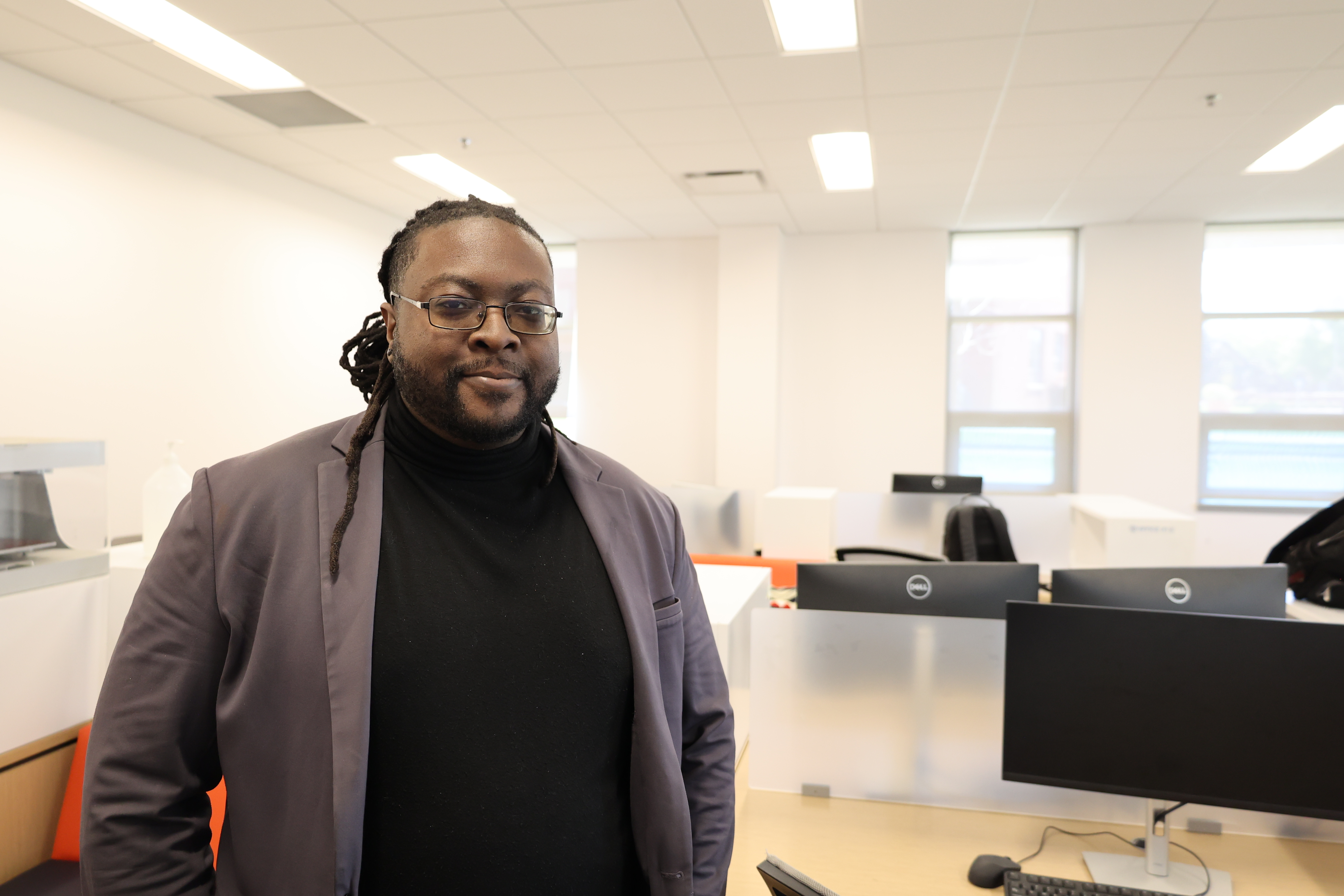 Photo of JSU graduate student Brandon Newton standing in a room with computers