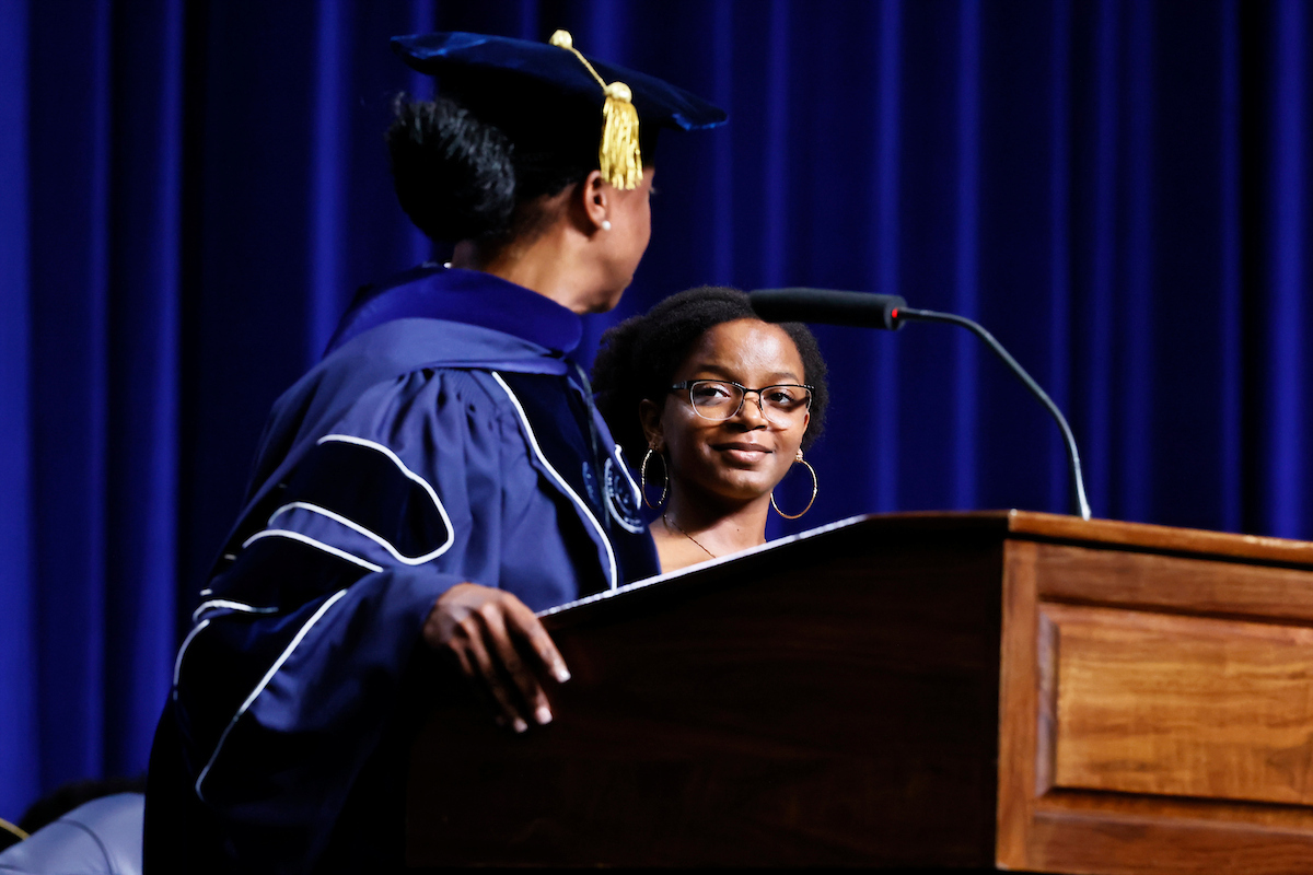 Dr. Gregory speaks to student on stage