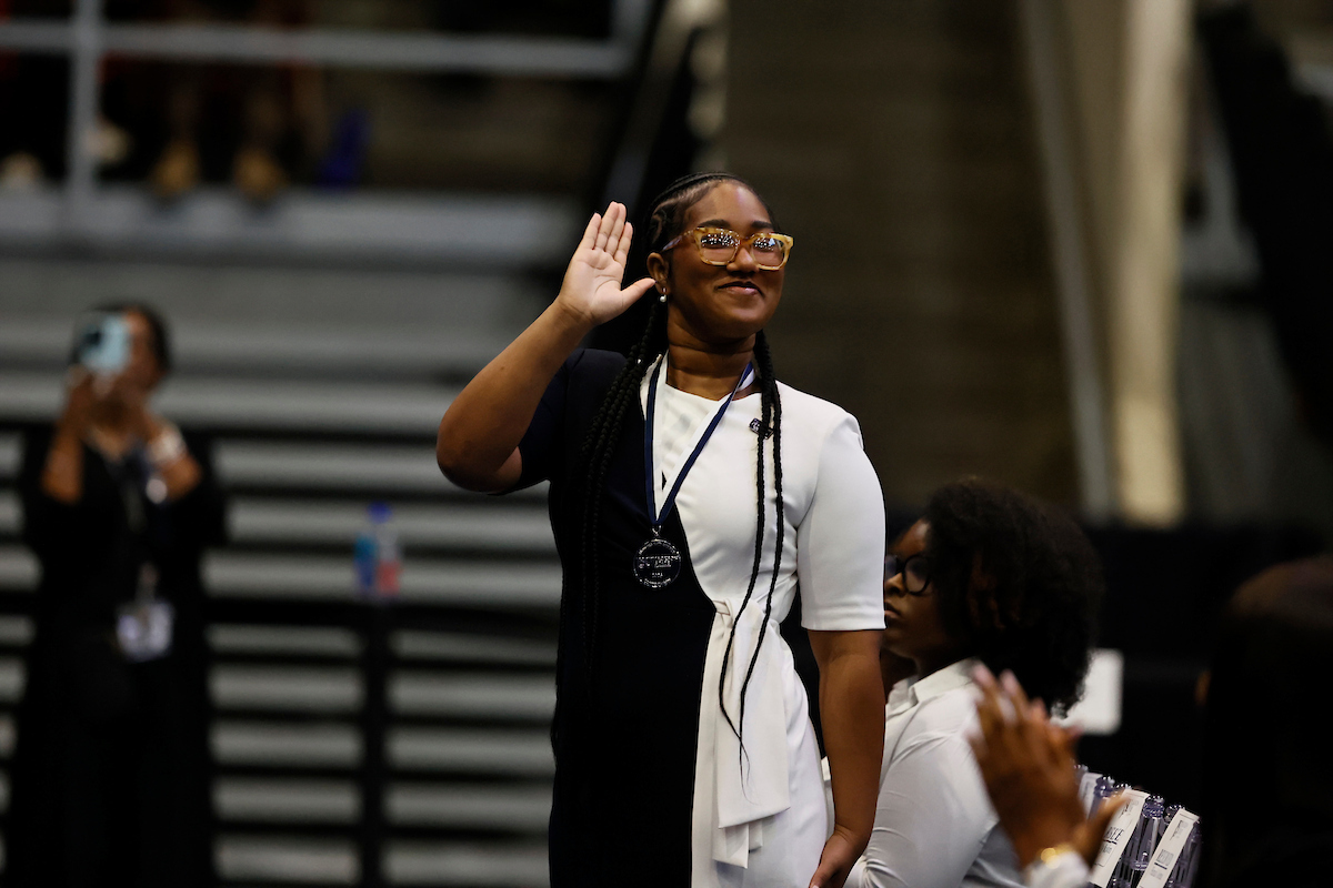female student smiles and waves
