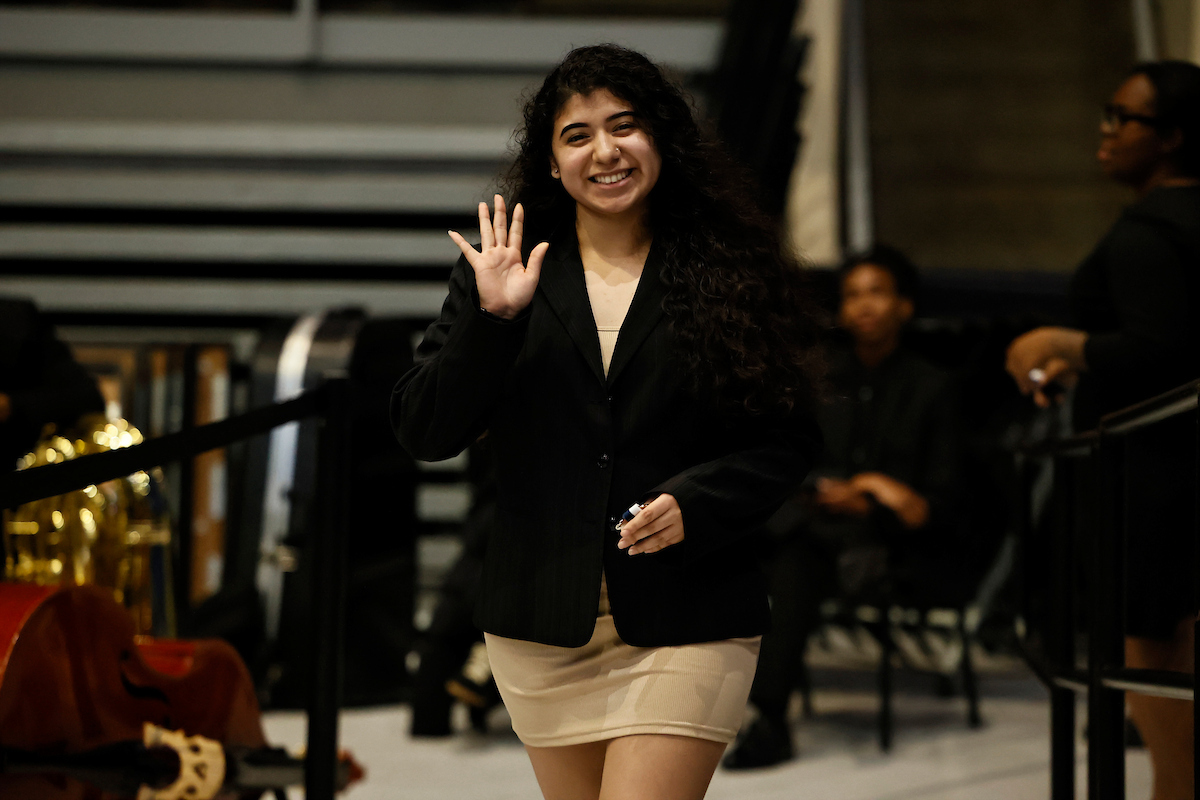 female student smiling and waving
