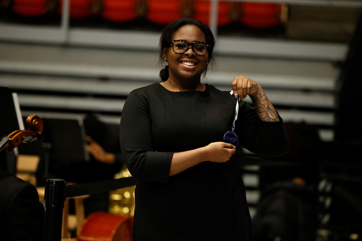 female student smiling and holding medal