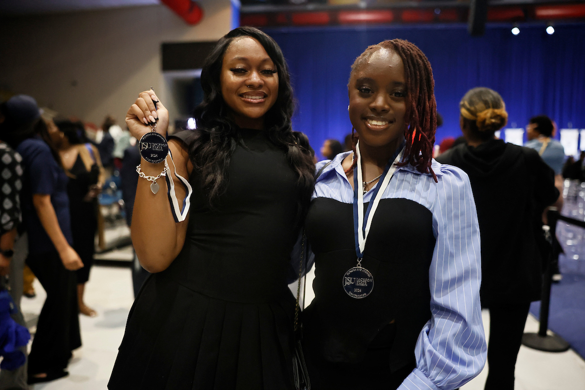 two female students smile with medals