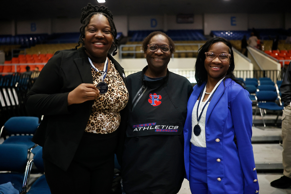 female students smile with medals and guest