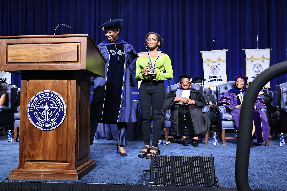 Dr. Gregory hugs student on stage