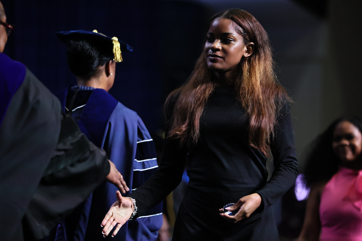 student shaking hands with faculty and staff